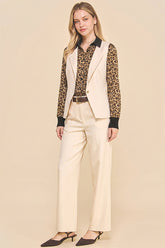 Woman wearing Oyster Belted Wide Leg Trousers paired with a leopard print blouse and beige sleeveless blazer, styled for a timeless, modern capsule wardrobe look.
