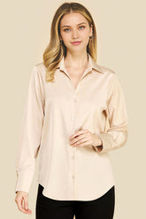 Woman wearing an Oyster Satin Blouse in a soft beige tone, featuring a classic collar and button-down front, styled simply for a timeless, minimalist capsule wardrobe look.