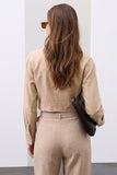 Back view of a woman wearing The Portofino Linen Set in a neutral beige tone, featuring clean lines and a timeless minimalist design, holding a dark textured clutch.