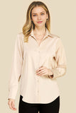 Woman wearing an Oyster Satin Blouse in a soft beige tone, featuring a classic collar and button-down front, styled simply for a timeless, minimalist capsule wardrobe look.