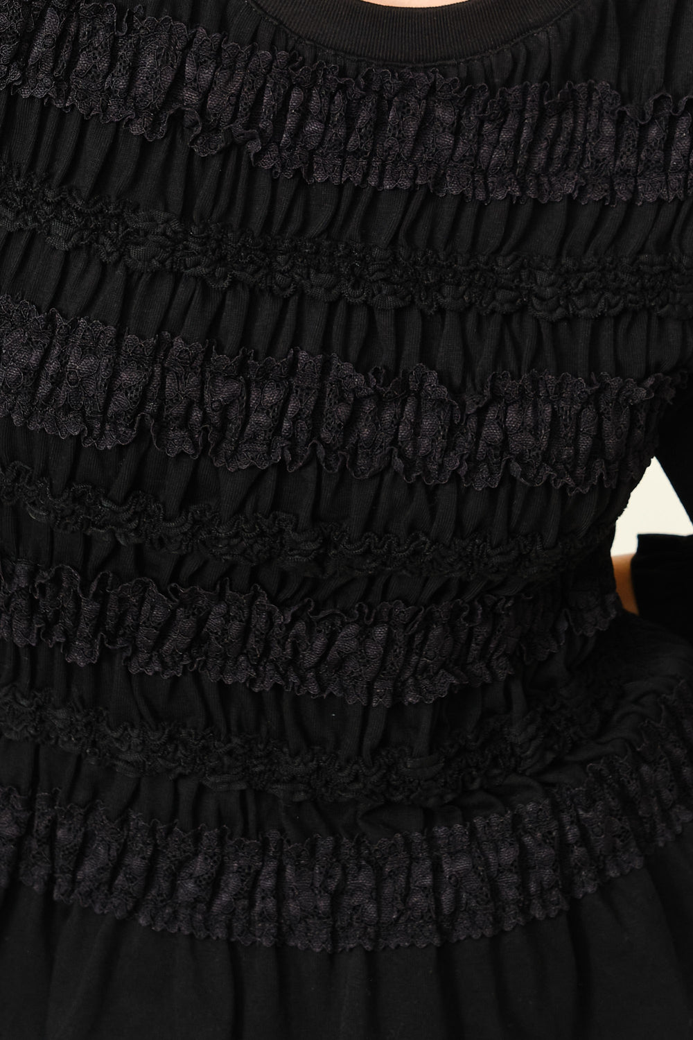 Close-up of The Vivienne Peplum Blouse showcasing its textured, ruched black fabric with delicate lace detailing, reflecting timeless minimalist design for a refined capsule wardrobe.