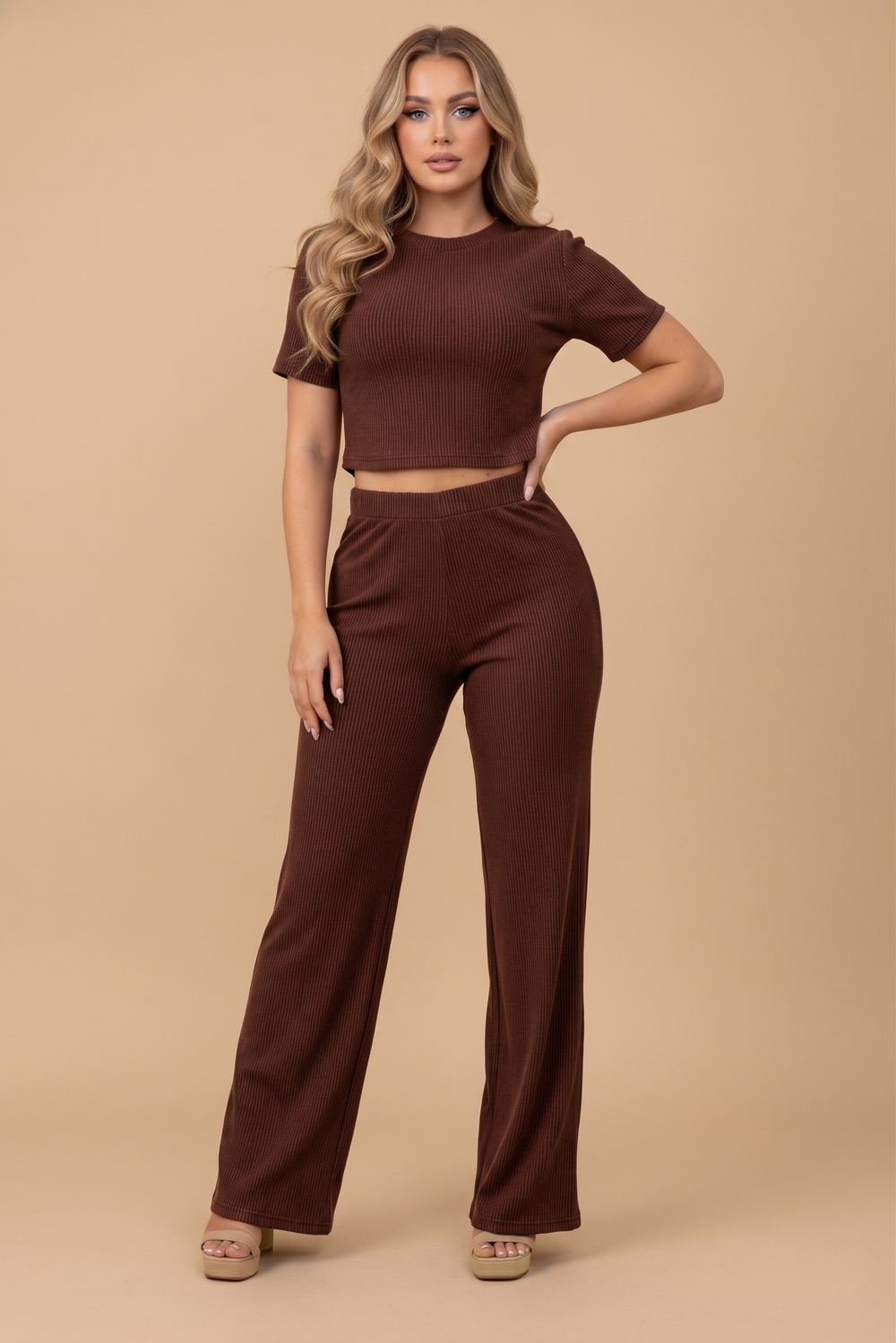 A woman wearing The Siena Lounge Set in a rich burgundy color, featuring a ribbed short-sleeve crop top and matching high-waisted wide-leg pants, styled with minimal accessories against a neutral background.