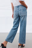 Rear view of a model wearing light blue distressed Camden Ankle Jean with a relaxed straight leg cut, paired with black heeled sandals and a tucked white top, showcasing timeless minimalist denim style.