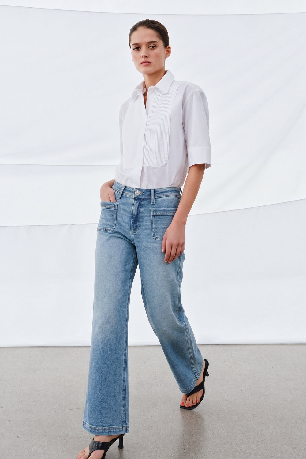Woman wearing light blue Camden Ankle Jean styled with a white half-sleeve blouse, showcasing a timeless, minimalist look perfect for a refined, modern capsule wardrobe.