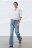 Woman wearing light blue Camden Ankle Jean styled with a white half-sleeve blouse, showcasing a timeless, minimalist look perfect for a refined, modern capsule wardrobe.