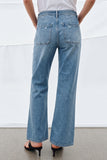 Back view of a person wearing light blue denim Camden Ankle Jean with a relaxed fit, slightly distressed patch pockets, paired with black heeled sandals and a white top.