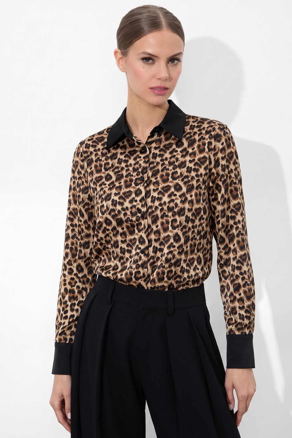 Woman wearing a Leopard Print Satin Blouse with black collar and cuffs, paired with high-waisted black trousers, showcasing a timeless minimal and refined capsule wardrobe piece.