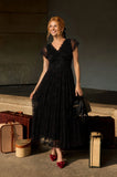 Orient Express Black Lace Maxi Dress – Whimsigoth Holiday & NYE Gown, woman wearing a flowing black lace gown with vintage luggage for a refined travel look