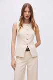 Model wearing The Oyster Longline Vest in a timeless minimalist design with clean lines and gold buttons, styled with matching trousers and a black belt for a refined capsule wardrobe look.