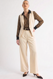 Woman wearing Oyster Belted Wide Leg Trousers paired with a leopard print satin blouse and a beige vest, styled with a black belt and pointed-toe heels, showcasing a refined, modern capsule wardrobe look.