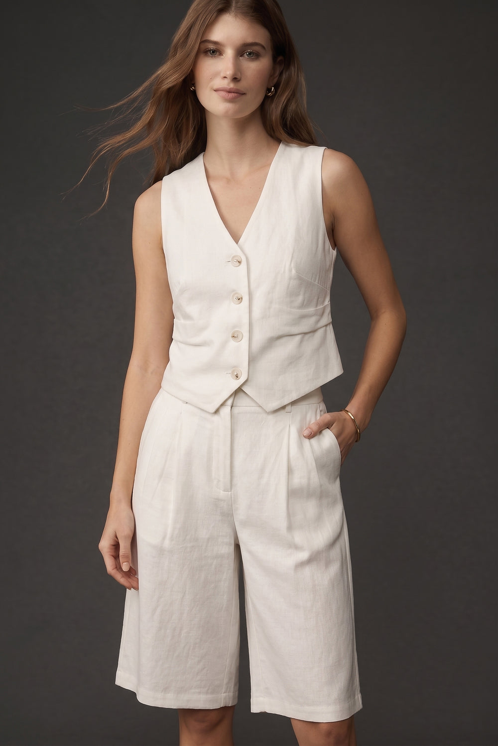 A model wearing The Palma Linen Set, featuring a sleeveless, button-front linen vest paired with high-waisted, knee-length wide-leg shorts in a minimalist, timeless design.