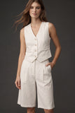 A model wearing The Palma Linen Set, featuring a sleeveless, button-front linen vest paired with high-waisted, knee-length wide-leg shorts in a minimalist, timeless design.