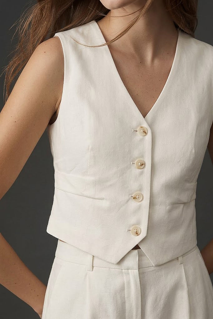 Close-up of a woman wearing The Palma Linen Set featuring a sleeveless, button-front linen vest in a soft ivory tone, showcasing clean lines and minimalist design.
