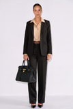 Model wearing The Worth Avenue Trousers styled with a black tailored blazer, beige satin blouse, and carrying a structured black handbag, embodying timeless minimalism and refined capsule wardrobe essentials.